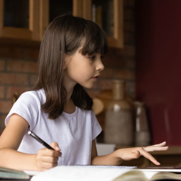 A girl doing her homework at the kitchen table, safe at home