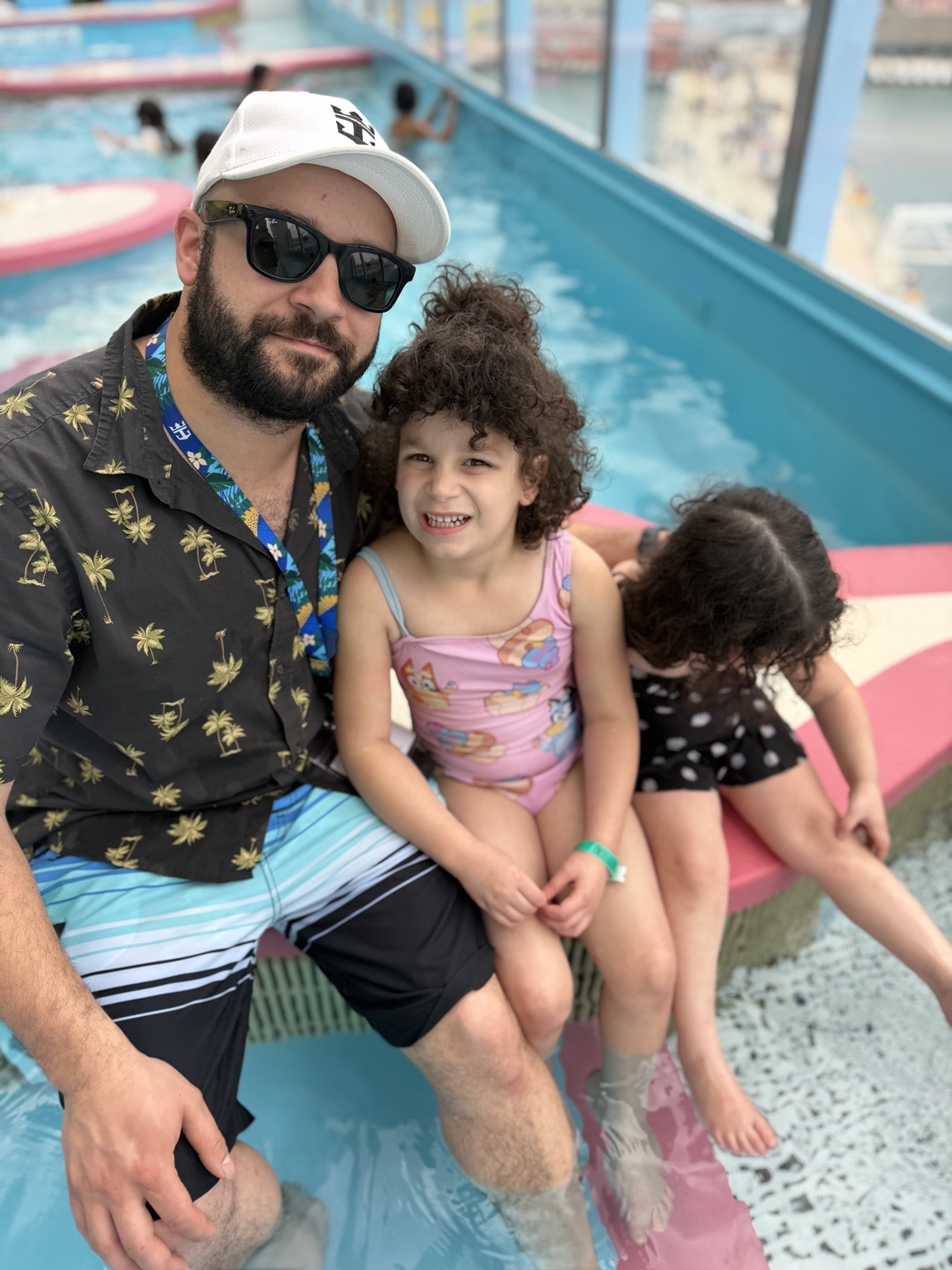 Chris and his daughters smiling together by the pool