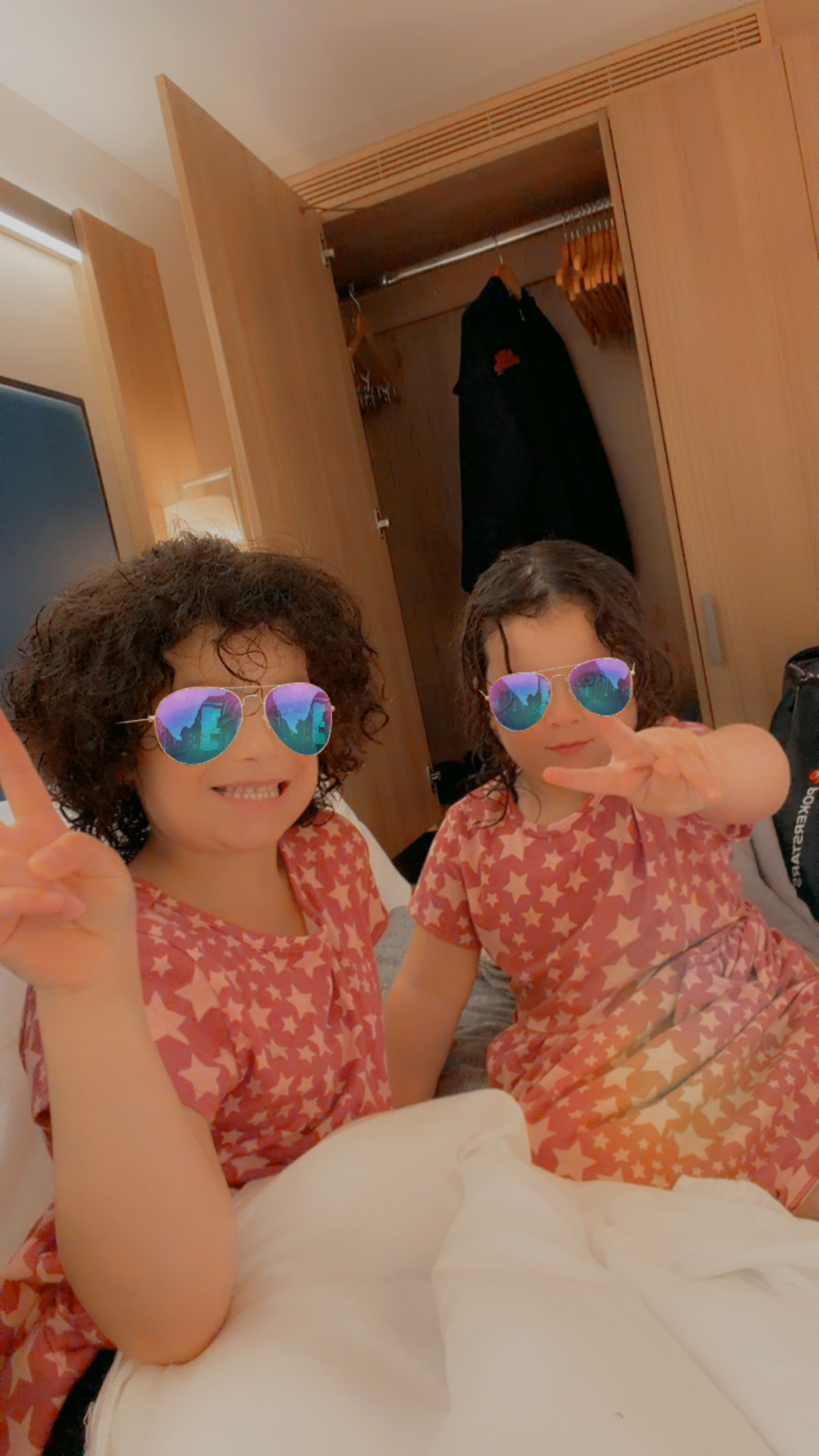 Two daughters in matching star-print dresses having fun with a sunglasses filter